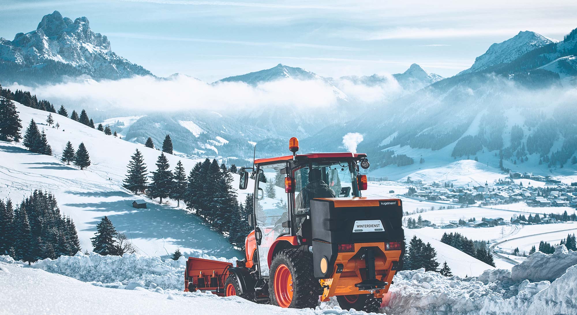 Kleiner Traktor mit Kugelmann Deipunktstreuer in tief verschneiter Landschaft